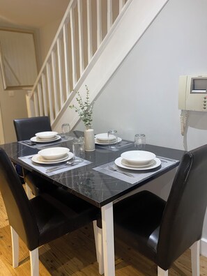 A dining table set with plates, cutlery, and a vase with greenery.