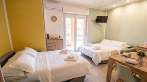 Ein Hotelzimmer mit zwei Betten, einem Esstisch, einem Fernseher und einem Balkon.