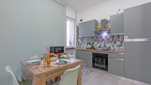 Eine moderne Küche mit grauen Schränken, einem Holztisch und einer Mikrowelle.