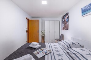 A modern bedroom with a bed, a chair, a wardrobe, and a painting on the wall.