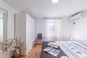 Un dormitorio moderno con cama, una silla, armario y ventana con cortinas translúcidas.