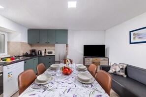 A modern kitchen with a dining area, a flat-screen TV, and a painting on the wall.