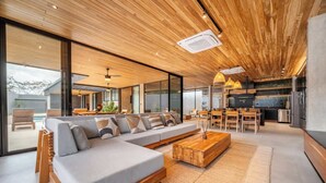 A modern living room with a large sectional sofa, wooden coffee table, and a dining area with chairs and a table. - Architect-Designed Villa Pool & Chef's Kitchen (Playa Grande)