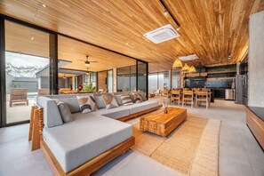 Ein modernes Wohnzimmer mit einer großen Eckcouch, einem Holztisch und einem Essbereich mit Stühlen und einem Tisch.