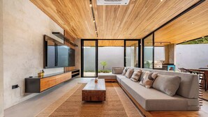 A modern living room with a wooden ceiling, a large flat-screen TV, a sofa, and a coffee table. - Architect-Designed Villa Pool & Chef's Kitchen (Playa Grande)