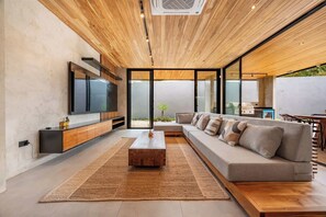 Ein modernes Wohnzimmer mit Holzboden, einem großen Flachbildfernseher, einer Couch und einem Couchtisch.