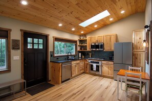 A kitchen with wooden cabinets, a refrigerator, a microwave, and a sink. - Private Evergreen Hideaway (Sequim)