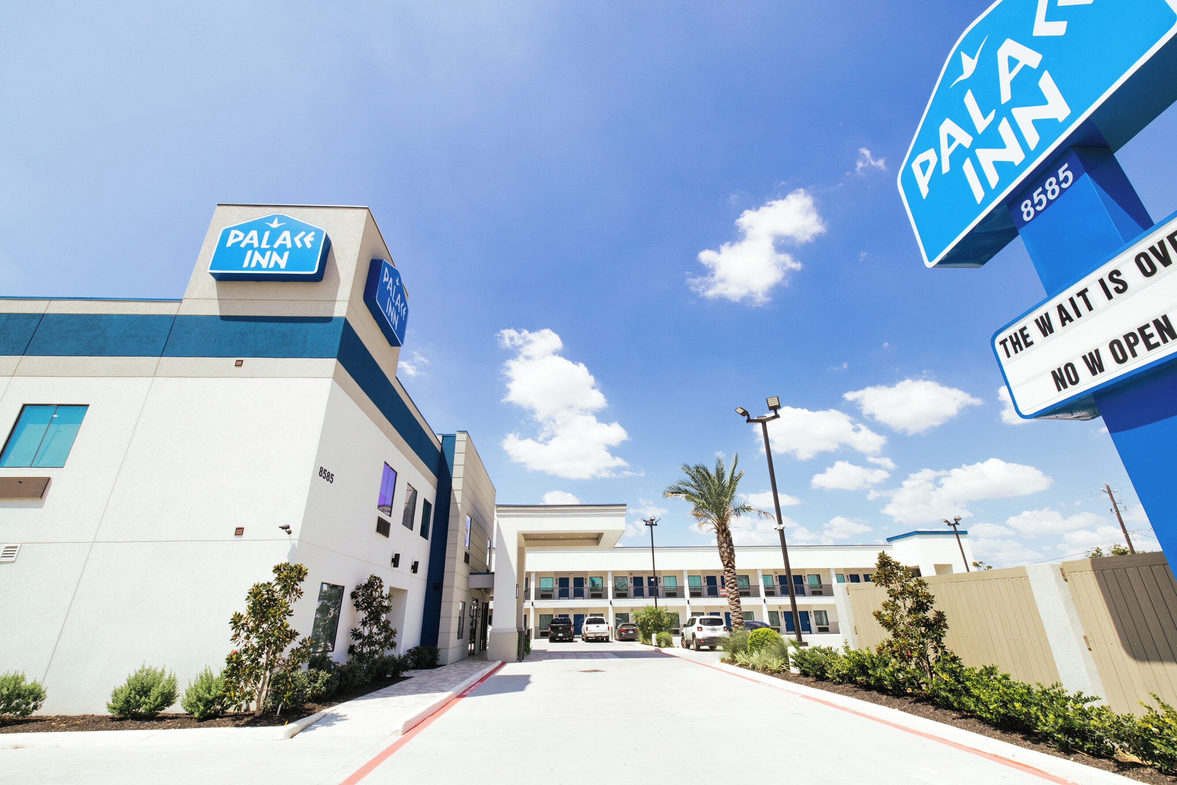 A hotel with a sign reading 'Palace Inn' and 'The Wait is Over, No Wait Open.'