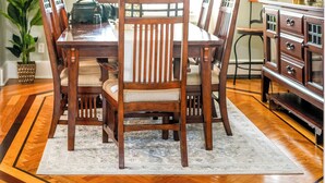 A dining room with a wooden table, chairs, a chandelier, and a cabinet.