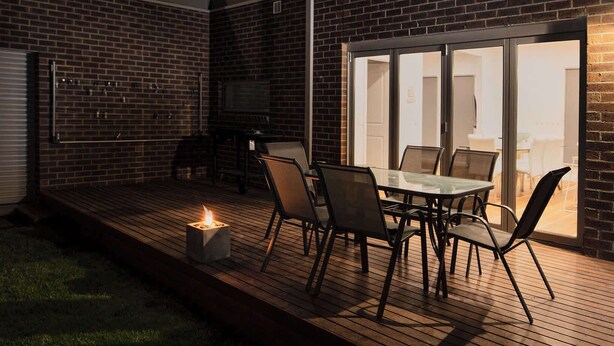 A patio with a table and chairs, a fire feature, and a brick wall.