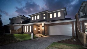 A modern two-story house with a garage, a well-lit entrance, and a driveway.