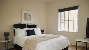 A bedroom with a bed, bedside tables, a mirror, a window, and a television. - Templestowe Village - 2BR, Parking, Pet-Friendly (Templestowe)