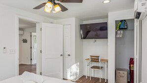 A bedroom with a bed, a desk with a chair, a television, and a wardrobe. - Bonfire Studio • King Bed • Pet Friendl (Lakeland)