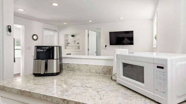 A kitchen with a stainless steel coffee maker, a white microwave, and a granite countertop. - Bonfire Studio • King Bed • Pet Friendl (Lakeland)