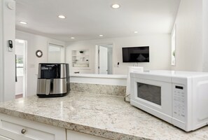 A kitchen with a stainless steel coffee maker, a white microwave, and a granite countertop. - Bonfire Studio • King Bed • Pet Friendl (Lakeland)