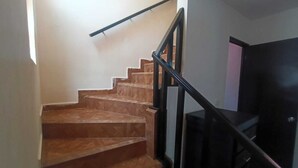 Uma escadaria com degraus de madeira e corrimãos pretos, que leva a um patamar.