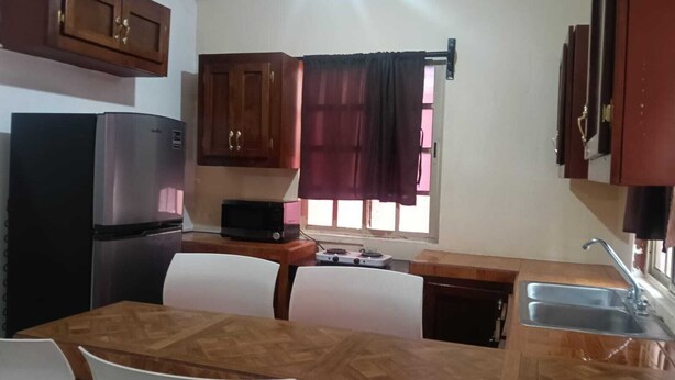 Cozinha equipada com frigorífico, micro-ondas, fogão e mesa de jantar com cadeiras.
