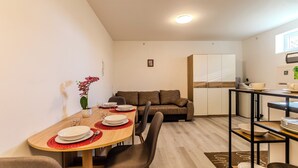A compact living space with a dining area, kitchenette, and a sofa.