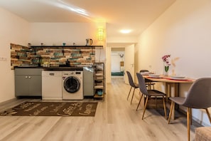 A compact kitchen with a washing machine, a coffee machine, and a built-in oven.