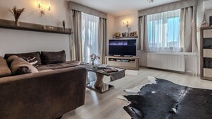 Ein modernes Wohnzimmer mit Sofa, Couchtisch, Fernseher und Dekorationselementen.