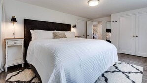 A bedroom with a large bed, bedside tables, a wardrobe, and a mirror. - TrackTown Retreat-Walk to Hayward Field & U of O (Eugene)