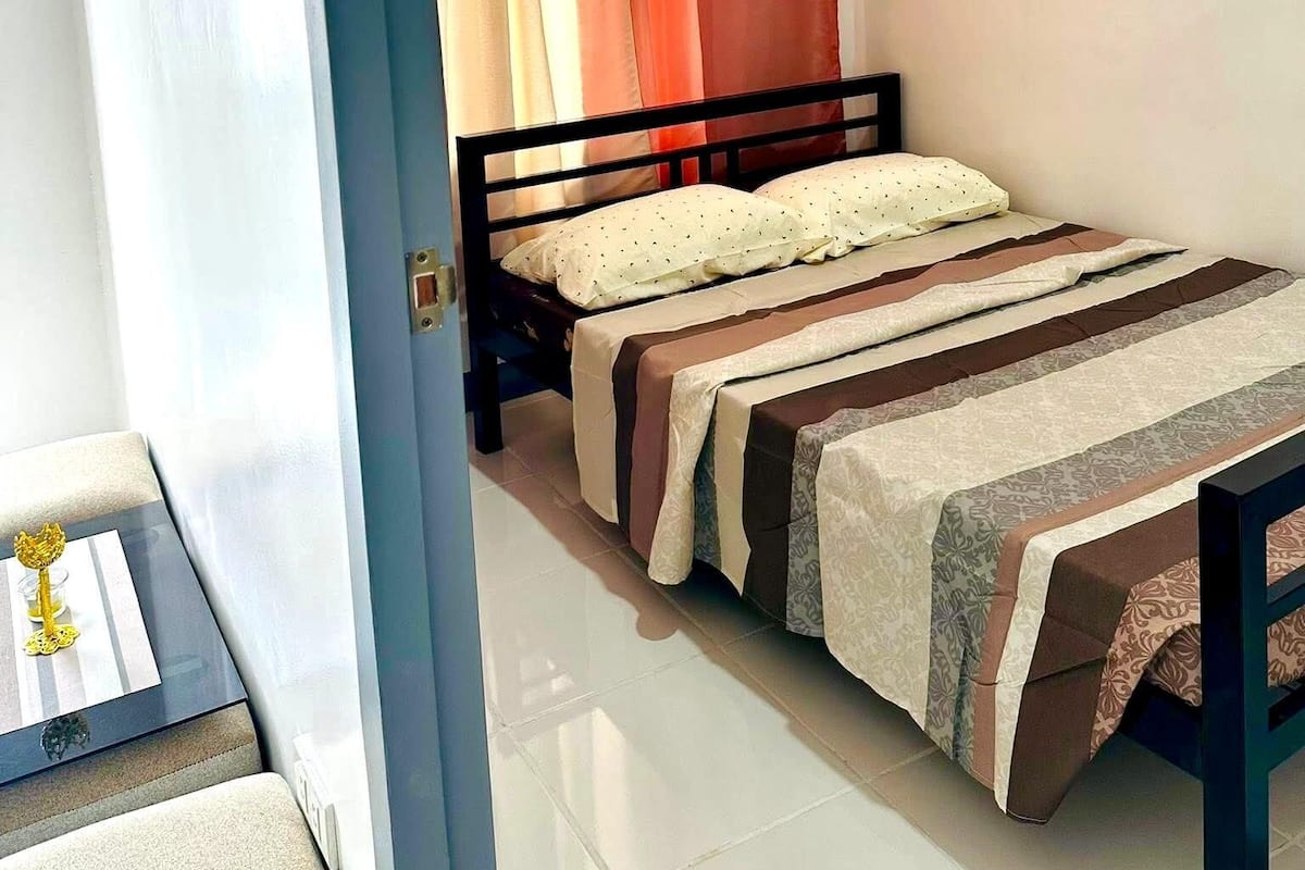 A bedroom with a bed, curtains, and a nightstand.