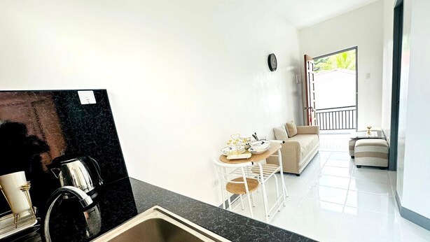 Eine moderne Küche mit Spüle, ein Essbereich mit Tisch und Stühlen, eine Sitzecke und ein Balkon mit Geländer.