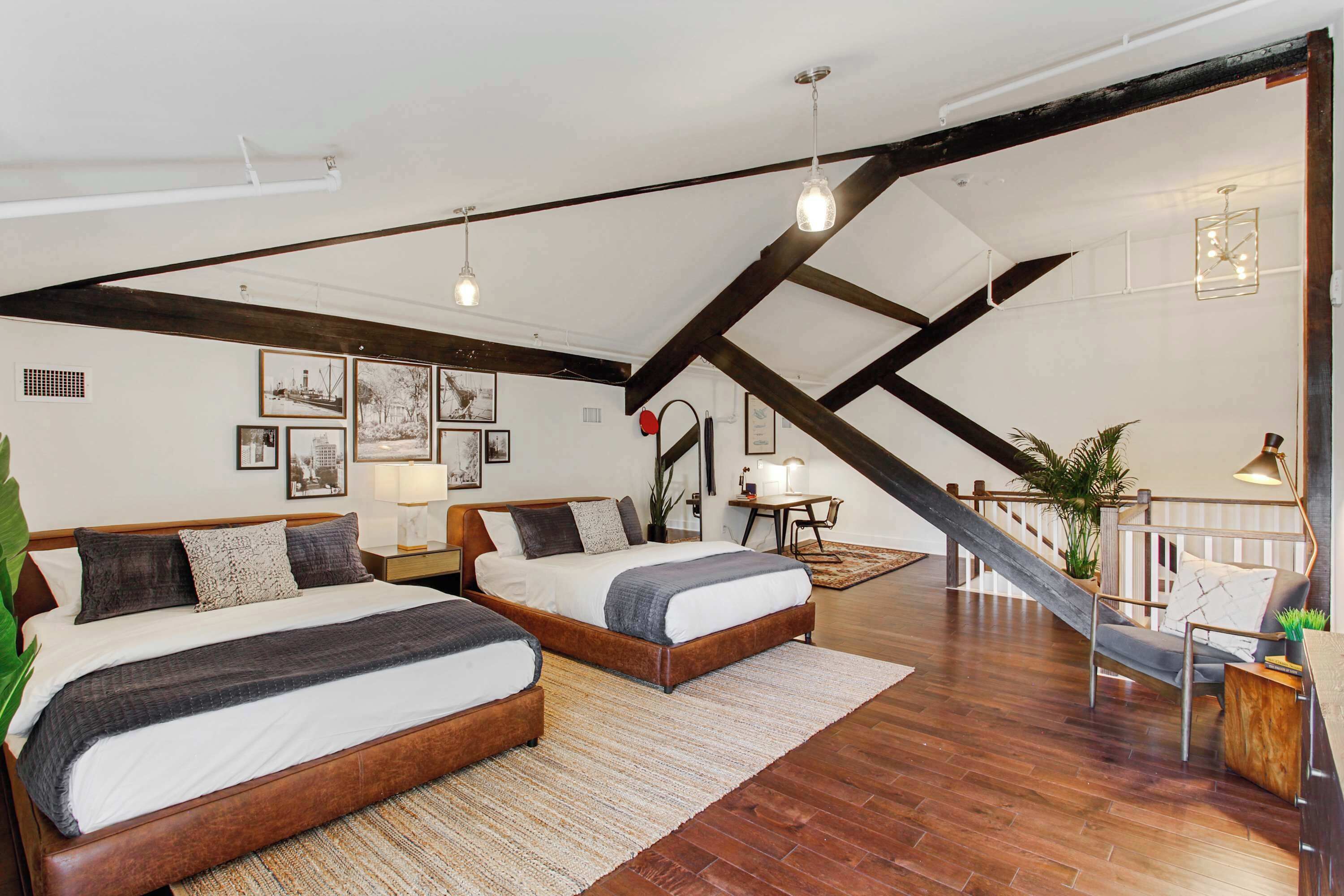 A spacious loft bedroom with two beds, a staircase, and a dining area.