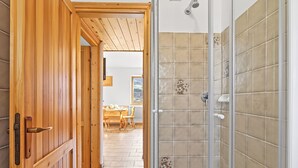 A wooden door leading to a room with a tiled shower wall.