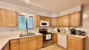 A kitchen with wooden cabinets, a stainless steel sink, a microwave, a stove, and a dishwasher.