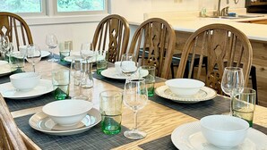 A dining area with a wooden table set for six, surrounded by wooden chairs.