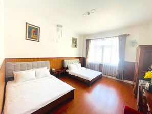 A hotel room with two beds, a wooden floor, a nightstand, a telephone, and a window with curtains. - Diamond Suite Dai Nam Hotel (Can Tho)