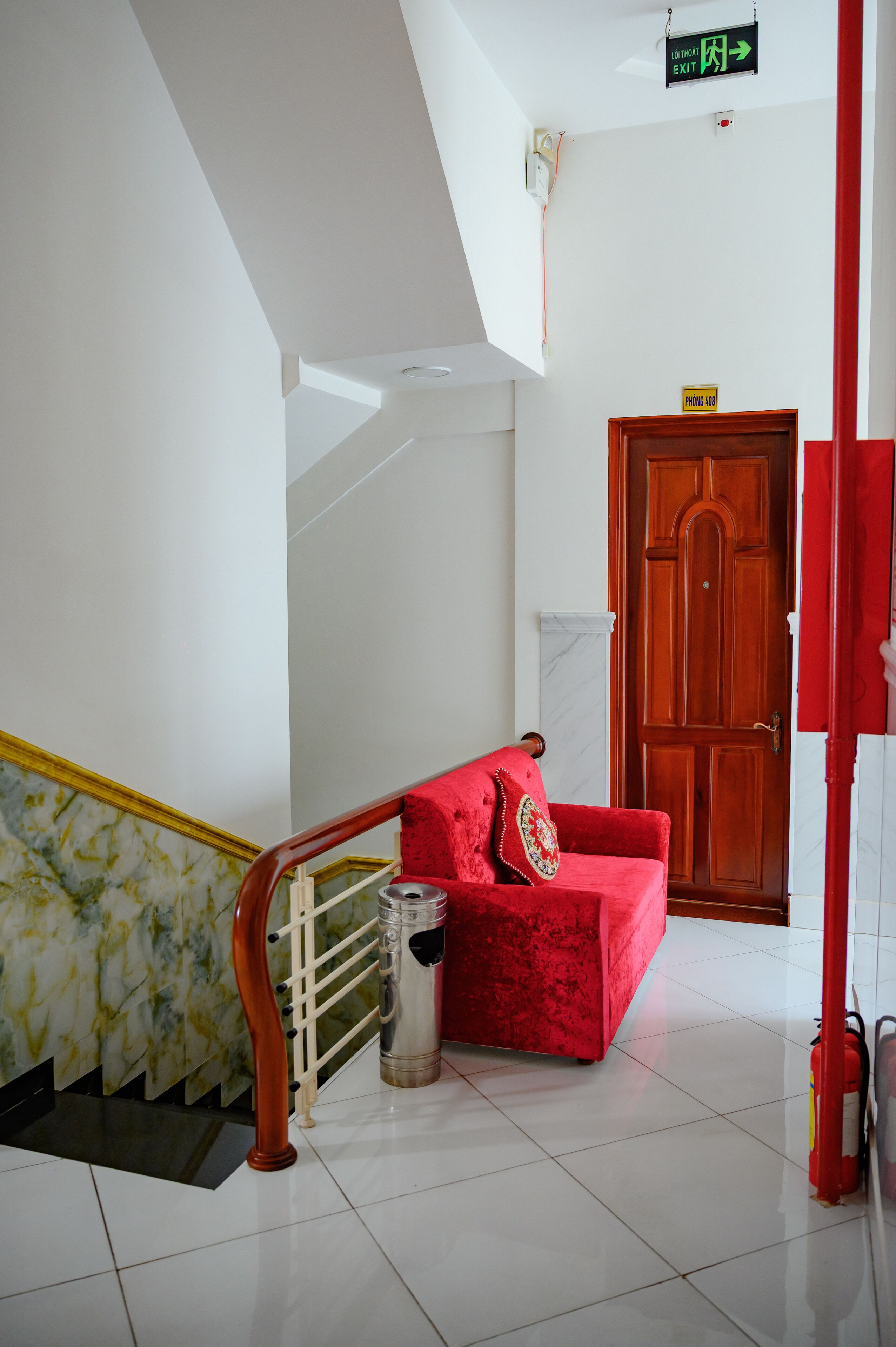 Un escalier avec une chaise rouge, une porte en bois et un extincteur.