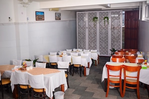 A restaurant with multiple tables and chairs, a decorative partition, and a door. - Diamond Suite Dai Nam Hotel (Can Tho)