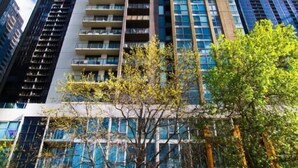 A tall, modern building with multiple floors and large windows, surrounded by other high-rise buildings. - Exclusive Stays - The Sentinel  (Southbank)