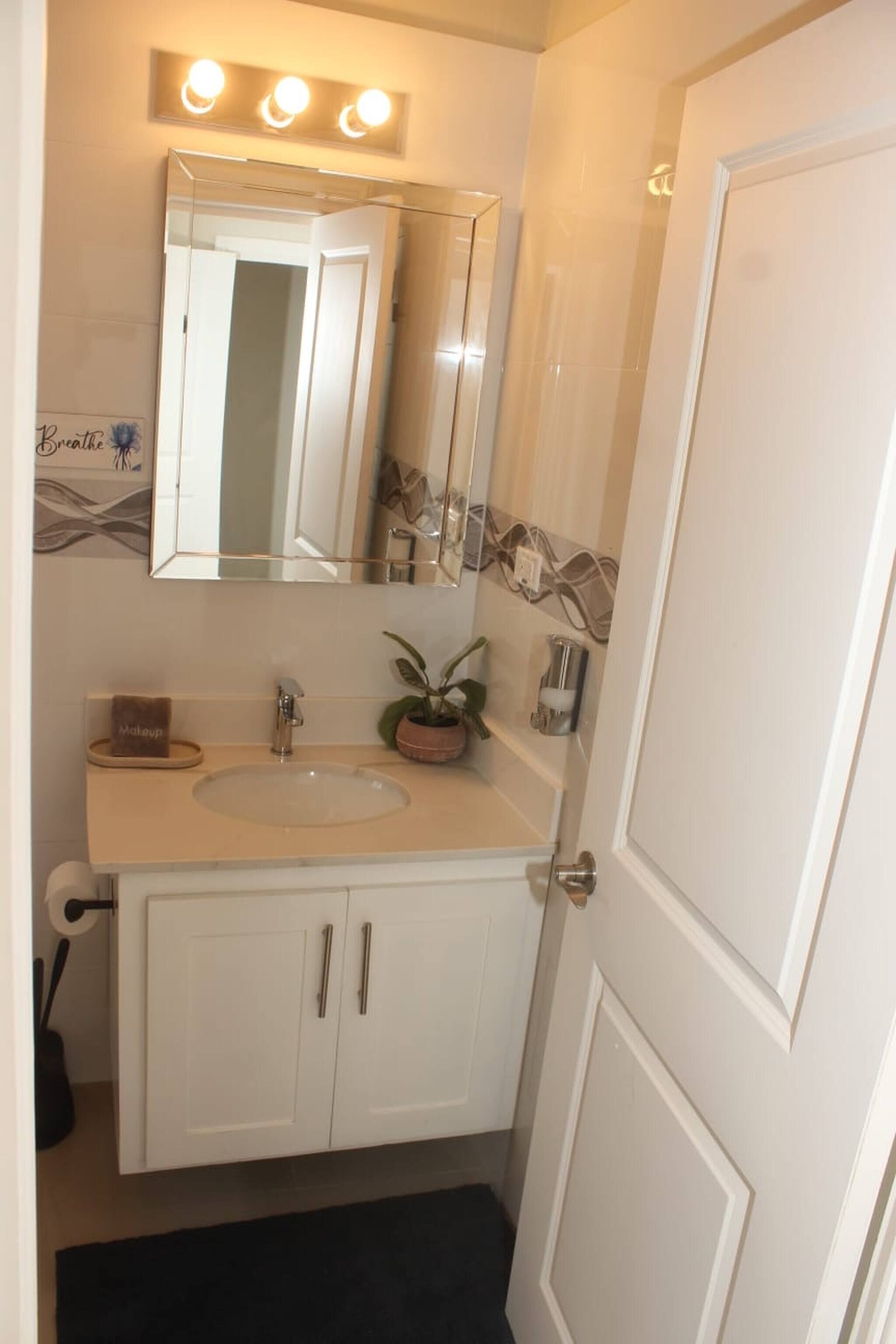 A bathroom with a sink, mirror, vanity, and a door.