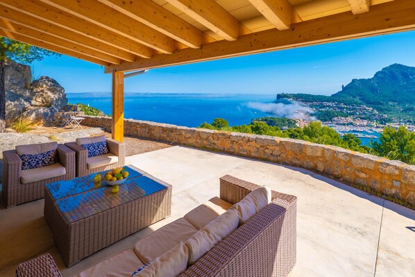 Un espace extérieur abrité, aménagé avec des meubles en osier et offrant une vue sur la mer.