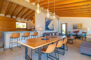 Una cocina amplia con una mesa y sillas de madera, un rincón de comedor con sofá y vistas al exterior.