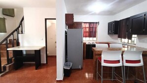 A compact kitchen with a refrigerator, a dining table with chairs, and a staircase. -  Casa Villegas B céntrica en Linares - WiFi 100MB y asador (Linares)