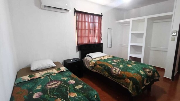 A bedroom with two beds, a wardrobe, and a ceiling fan. -  Casa Villegas B céntrica en Linares - WiFi 100MB y asador (Linares)