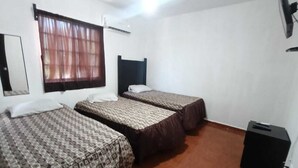 A room with two beds, a window with curtains, a wall-mounted air conditioner, and a black speaker. -  Casa Villegas B céntrica en Linares - WiFi 100MB y asador (Linares)