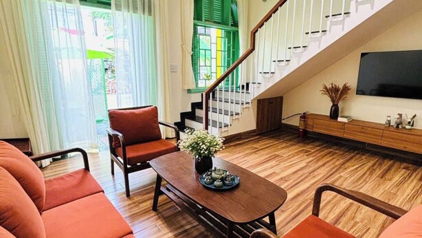 Un salon avec un escalier, un plancher en bois et un ventilateur de plafond.
