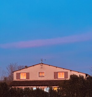 Ein zweistöckiges Haus mit geneigtem Dach, Schornstein und Satellitenschüssel.