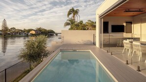 A modern house with a swimming pool, outdoor seating, and a view of a body of water. - Maison by Khove (Broadbeach Waters)
