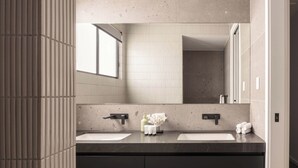Un baño moderno con dos lavamanos, un espejo grande y una ventana.