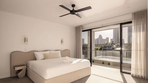 Una habitación de hotel moderna con cama, ventilador de techo, ventana grande con vista a la ciudad y balcón.