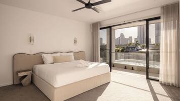 A modern hotel room with a bed, a ceiling fan, a large window with a city view, and a balcony.