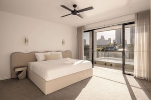 A modern hotel room with a bed, a ceiling fan, a large window with a city view, and a balcony. - Maison by Khove (Broadbeach Waters)