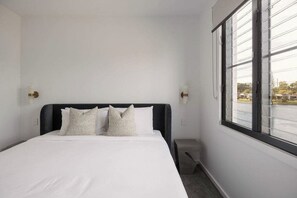 Ein Hotelzimmer mit Bett, Fenster und Nachttisch.