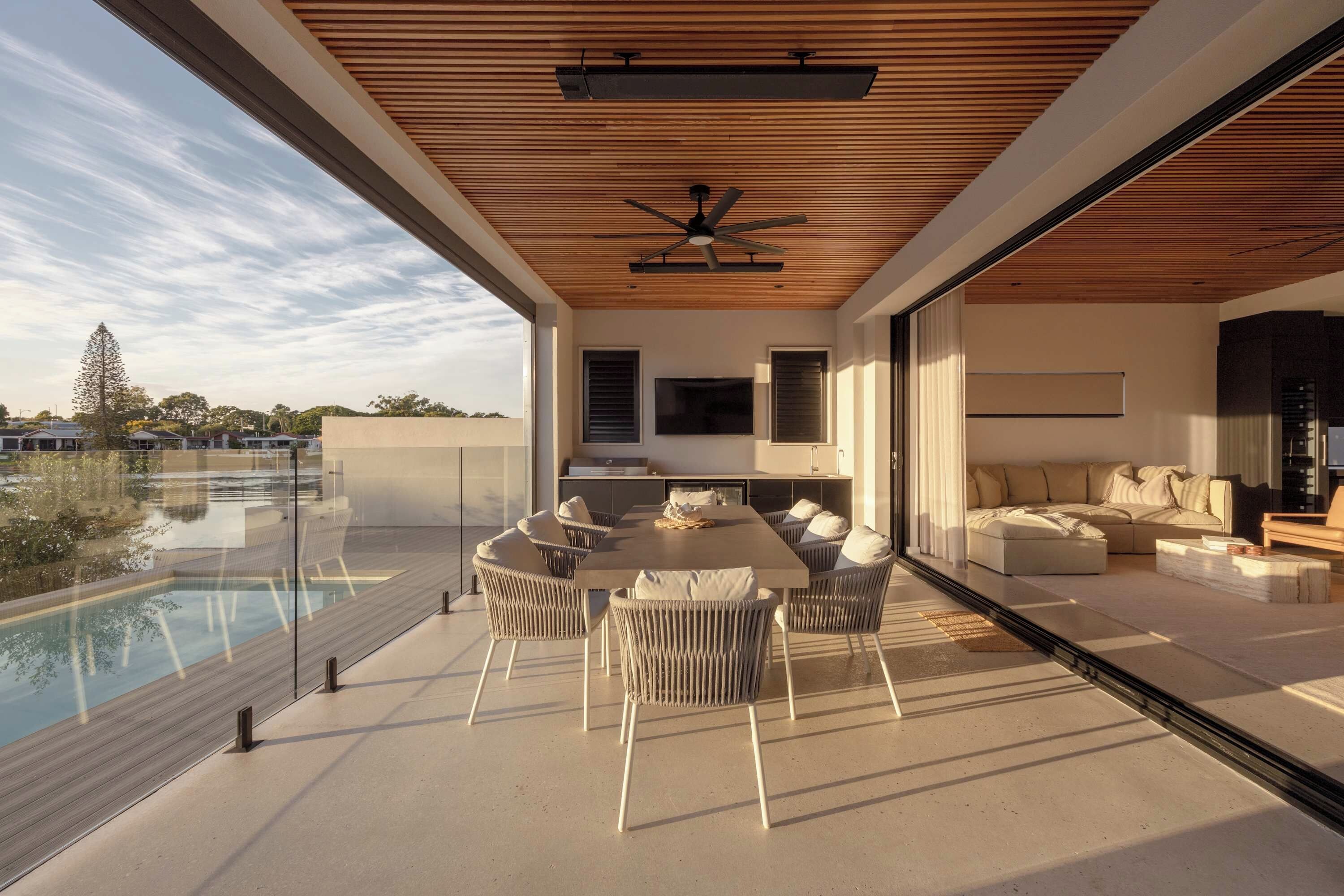 A modern living space with a pool, outdoor furniture, and a large flat-screen TV.